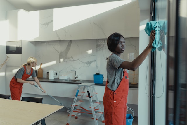 A couple of people cleaning the inside of a house.