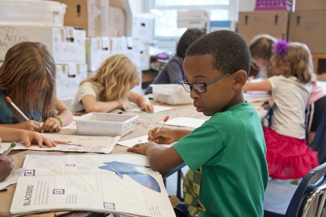 children writing at tables at school